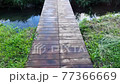Cross the wooden bridge above the stream 77366669