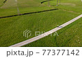 Man cycling along gravel road across the meadow. 77377142
