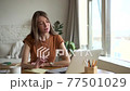Young woman talking in front of laptop screen during online education at table at home. 77501029