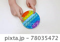 Popit antistress toy for children entertainment on a yellow background playing a child top view in colored fijit simple dimple popit silicone fidget, trendy sensory color push 78035472