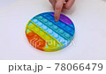 Popit antistress toy for children entertainment on a yellow background playing a child top view in colored fijit simple dimple popit silicone fidget, trendy sensory color push 78066479