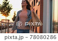 Stylish smiling beautiful young shopping woman in casual with bags packages walking outdoors at sunset street city 78080286