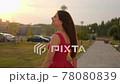 Cute smiling beautiful young shopping female in red dress with bags packages walking outdoors street city 78080839