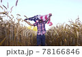 Little kid holding an American flag on the wind in a field of wheat. Summer landscape against the blue sky. 78166846