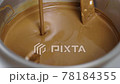 jet of melted milk chocolate pours into smoll mixer or stirrer. 78184355