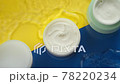 Cosmetic jars of moisturizing cream in clean water splash on colorful background 78220234