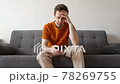 Procrastination. Young caucasian man with a mobile phone at home on the couch is passing time 78269755
