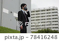 A business person wearing a mask and coughing while making a phone call outdoors in Corona 78416248