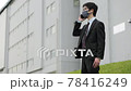 A business person wearing a mask and coughing while making a phone call outdoors in Corona 78416249