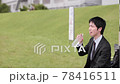 A smiling business person holding a plastic bottle in the park 78416511