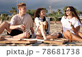 Friends having a picnic with pizza and beer on the beach at sunset. 78681738
