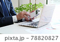 A businessman operating a calculator in front of a computer 78820827