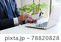 A businessman operating a calculator in front of a computer 78820828