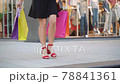 Close up of young woman's legs and colorful shopping paper bags 78841361