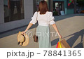 Young woman walks with colorful shopping bags around shopping mall. 78841365