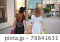 Young women walks with colorful shopping bags around shopping mall. 78841631