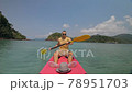 Man with sunglasses and hat rows pink plastic canoe along sea against green hilly islands with wild jungles. Traveling to tropical countries. Man with sunglasses and hat rows pink plastic canoe along sea against green hilly islands with wild jungles. Traveling to tropical countries. 78951703