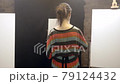 Artist girl with paints and brushes walks through the workshop to the easel. 79124432