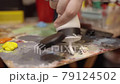 Womam squeezing oil paint from a tube onto a palette 79124502