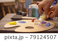 Womam artist is squeezing oil paint from a tube onto a palette. 79124507