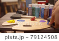 Womam artist is squeezing oil paint from a tube onto a palette. 79124508