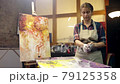 Woman artist is taking off her painting glosves after aristic workshop and leaving. The job is done. 79125358