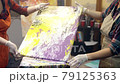 Wome artists are making acrylic paintings. Acrylic paint is spreading over the canvas. Artistic collaboration in workshop. 79125363