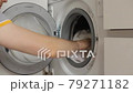 Men's hands load white laundry into the washing machine. Preparing the laundry for washing, side view 79271182