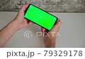 a man at a white Desk is sitting with a mobile phone in his hands with a green screen. swipes and taps on the smartphone's chromakey screen in close-up. ready-made video for inserting and keying 79329178