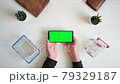a phone with a green chromakey screen and a shopping cart on a white background. top View of the smartphone in the hands of a close-up 79329187