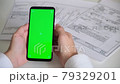 Phone with green screen and payment receipts, tax documents on white background top View . smartphone chromakey swipes in different directions. copy space 79329201