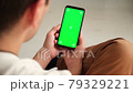 Handheld Camera: Point of View of Woman at Phone with Green Screen for Copy Space. Chromakey 20s Lady Watching Video News on Couch Close up. Tap to Click on Centre of Screen 79329221