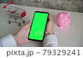 phone with a chromakey screen in the hands of a close-up . top view smartphone piggy Bank and shopping cart copy space on white background 79329241