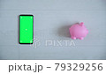 Phone with a green chromakey screen on a white background with a pink piggy Bank top view . smartphone copy space swipes in different directions 79329256