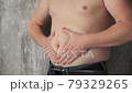 Close up fat man touch the Belly doing massage shaking. He very fat and has problem with stomach ache because he eat to much. .a man massages his stomach. fight against excess weight  79329265