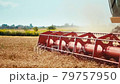 Rotary straw walker combine harvester cuts and threshes ripe wheat grain. Platform grain header with thresher reel, cutter bar reaping cereal ears. Gathering crop by agricultural machinery on field 79757950
