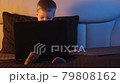 Cute caucasian boy in bedroom late at night sits on bed, typing on laptop keyboard, surfing Internet and closes notebook. night light in room, moonlight from window. Dolly slides through video. 79808162