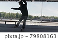 Teenager rides on back wheels of skateboard performing balance tricks on site of skate Park under an iron bridge. Professional skateboarder guy in dark clothing performs an trick on skateboard 79808163