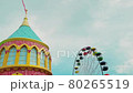 A rotating Ferris wheel in an amusement park against a blue sky. 80265519