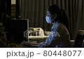 Woman wearing face mask to protect from coronavirus Covid-19 while working at home late at night 80448077