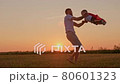 Happy family dad and son happily spinning together at sunset in rays of sun. Father plays with his son in summer in field in rays of sun. Happy family, an attitude in family, loving father and son. 80601323