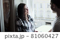 Young couple man and woman sitting on window sill and enjoying old town view. Happy young lovers enjoy time spending together at home 81060427