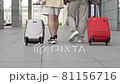 Couple with suitcases walking through the airport or train station. Back view. 81156716