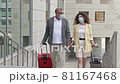 Mature married couple with suitcases is walking hand in hand. There are medical masks on the faces of passengers. Travel, tourism during the COVID-19 epidemic. 81167468