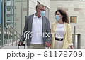Mature married couple with suitcases is walking hand in hand. There are medical masks on the faces of passengers. Travel, tourism during the COVID-19 epidemic. 81179709