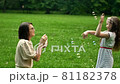 Beautiful young mother together with her daughter in nature making soap bubbles and laughing. 81182378