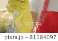 Female hands in yellow gloves cleaning window pane with rag and spray detergent. Washing windows with spray. 81184097