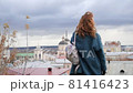 young red-haired woman in a blue coat and walks against the backdrop of the old city. portrait of a beautiful woman in the autumn city 81416423