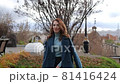 young red-haired woman in a blue coat and walks against the backdrop of the old city. portrait of a beautiful woman in the autumn city 81416424