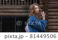 young red-haired woman in a blue coat and walks against the backdrop of the old city. portrait of a beautiful woman in the autumn city 81449506
